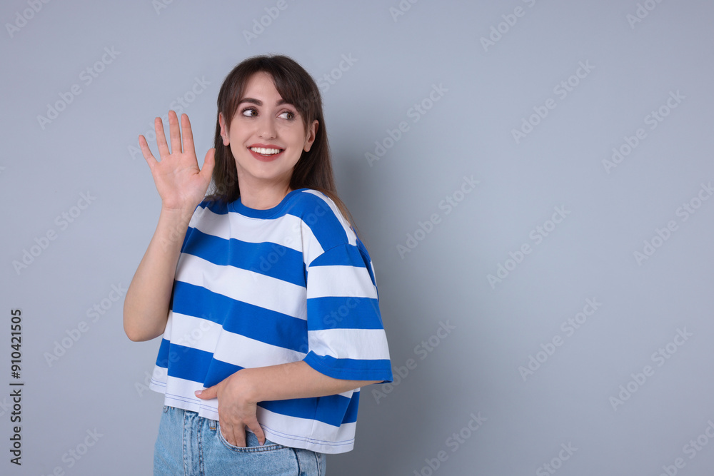 Happy woman waving on light grey background, space for text Happy woman waving on light grey background, space for text