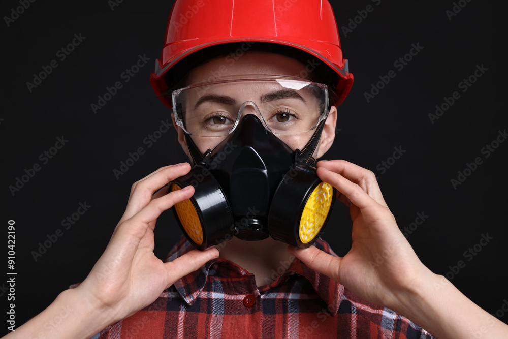 Woman in respirator, protective glasses and helmet on black background Woman in respirator, protective glasses and helmet on black background