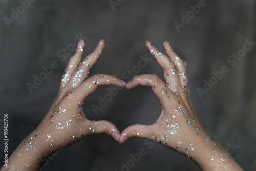 Selective focus on heart-shaped hands. Hands with sequins. The concept of the holiday