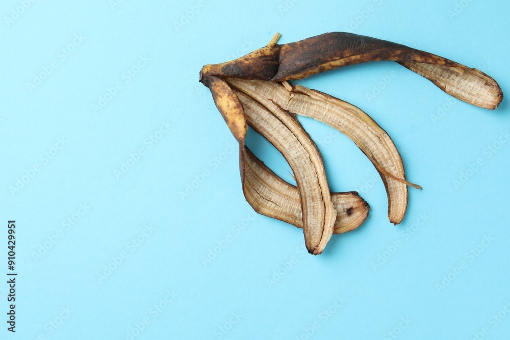 Banana peel with dark spots on light blue background, top view. Space for text Banana peel with dark spots on light blue background, top view. Space for text