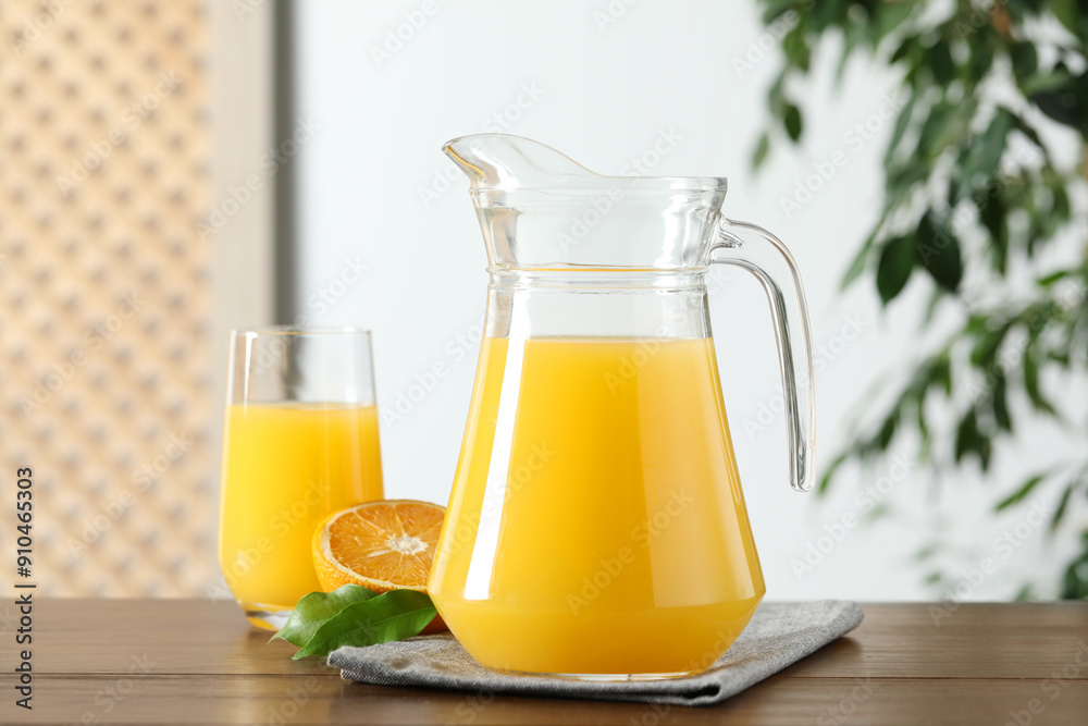 Tasty orange juice in jug, glass and citrus fruit on wooden table Tasty orange juice in jug, glass and citrus fruit on wooden table