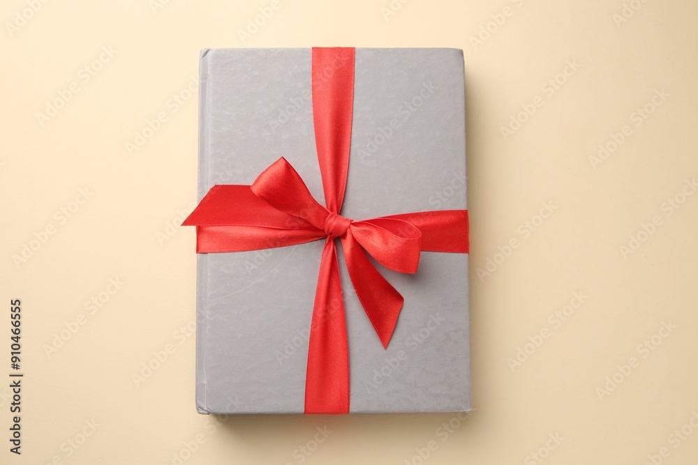Book tied with red ribbon on beige background, top view. Perfect gift Book tied with red ribbon on beige background, top view. Perfect gift