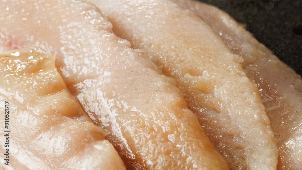 Raw herring fish slices a black plate close-up macro. Marinated herring fillet in oil and spices for appetizer. Raw seafood products Raw herring fish slices a black plate close-up macro. Marinated herring fillet in oil and spices for appetizer. Raw seafood products