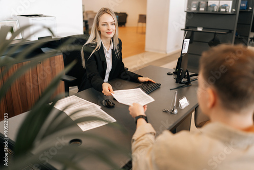 High-angle back view of female manager talking about business tasks with male colleague, giving papers documents at table in office. Recruiter ask applicant questions, interviewing job candidate