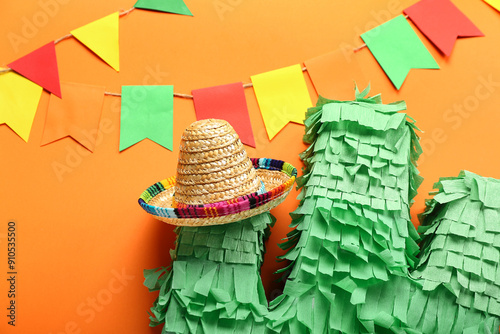 Mexican pinata with sombrero hat and flags on color background, closeup