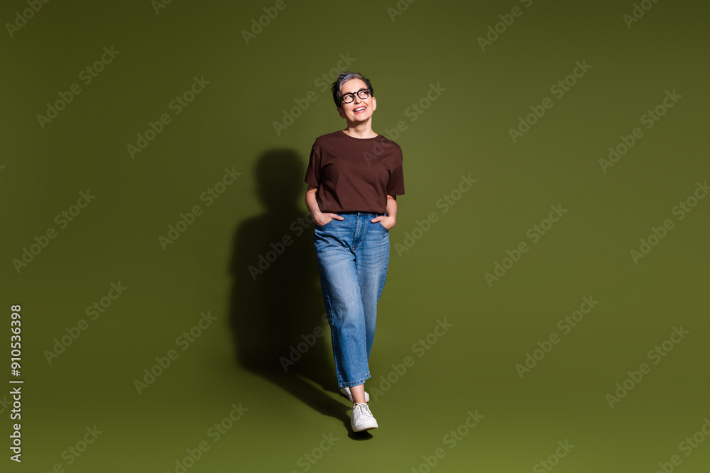 Full size photo of nice aged woman look empty space wear t-shirt isolated on khaki color background Full size photo of nice aged woman look empty space wear t-shirt isolated on khaki color background