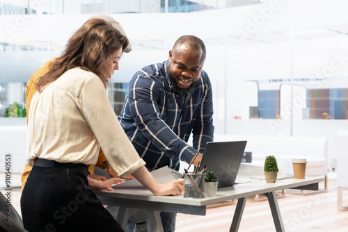 Salesman and contractor meeting with client to evaluate office space layout on blueprints in order to enhance her workspace vision. Experts assisting entrepreneur with property investment. photo