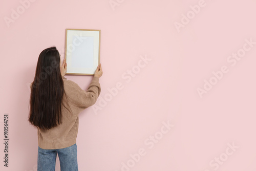 Young woman hanging picture...