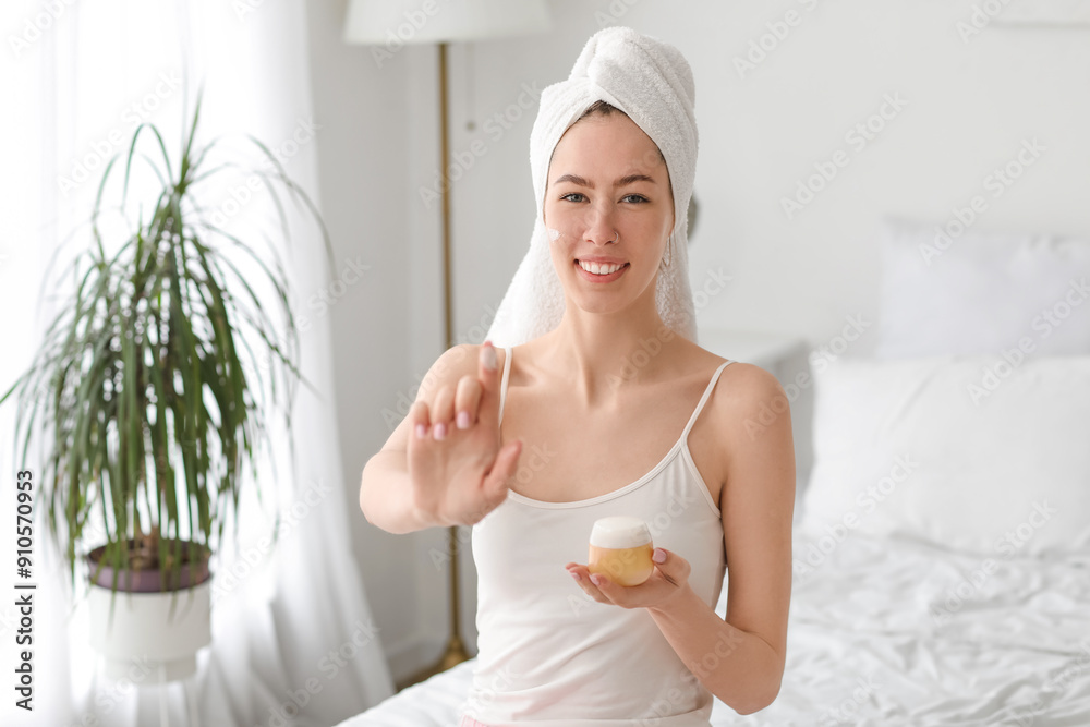 Φωτογραφία Beautiful young woman after shower showing jar of cream and pointing at somethin