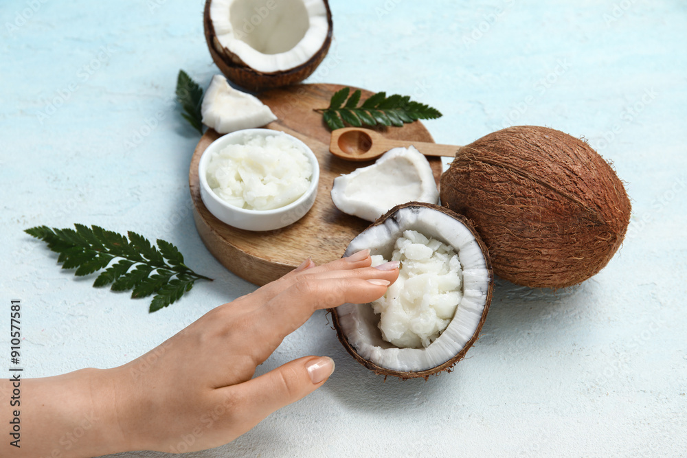 Female hand, wooden tray and bowl of natural coconut oil on blue grunge background, closeup Female hand, wooden tray and bowl of natural coconut oil on blue grunge background, closeup