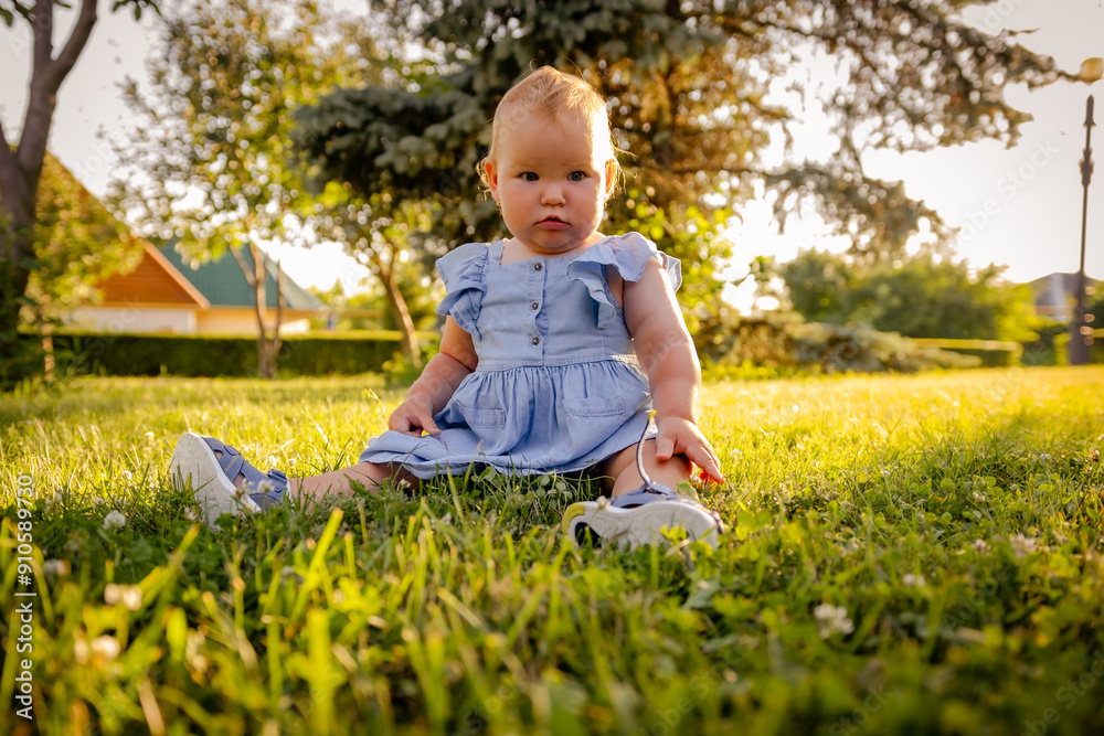 Curious Toddler Sitting on Green Grass in a Sunny Outdoor Setting at Golden Hour Curious Toddler Sitting on Green Grass in a Sunny Outdoor Setting at Golden Hour
