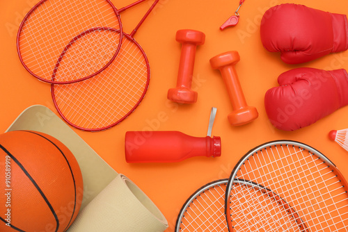 Fototapeta Naklejka Na Ścianę i Meble -  Sport equipment with dumbbells and rackets on orange background. Top view