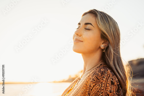 Portrait of one young woman at the beach with closed eyes enjoying free time and freedom outdoors. Having fun relaxing and living happy moments.. #910597191