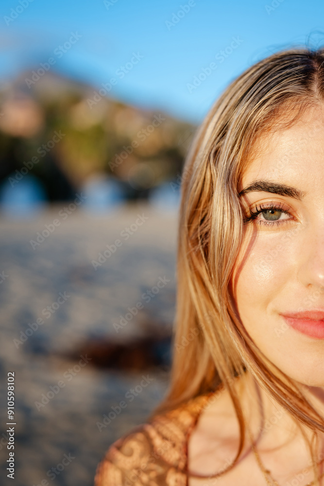 Portrait of one young beautiful woman looking at the camera with big blue and green eyes. Female girl at the beach close up face.