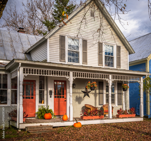 Charming old house during autumn with orange doors, decorated with pumpkins for fall season and Halloween. Photo taken in Montgomery Center, Vermont, New England, United States in October 2023.