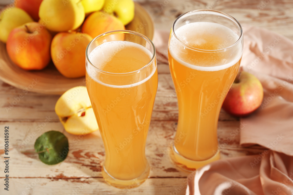 Glasses of fresh apple kvass and plate with fruits on white wooden background Glasses of fresh apple kvass and plate with fruits on white wooden background
