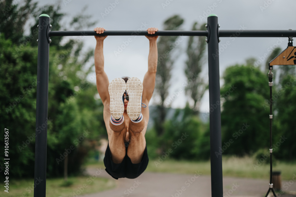 Man doing an outdoor calisthenics workout hanging on a horizontal bar in a park setting. Achieving strength and fitness goals. Man doing an outdoor calisthenics workout hanging on a horizontal bar in a park setting. Achieving strength and fitness goals.