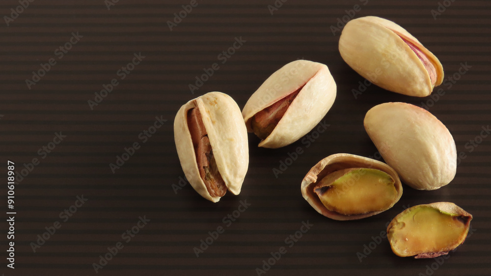 Roasted pistachio nuts in shell on black and brown striped background
Roasted pistachio nuts in shell on black and brown striped background