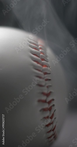 Baseball ball close-up rotating with smoke in studio slow motion, vertical view