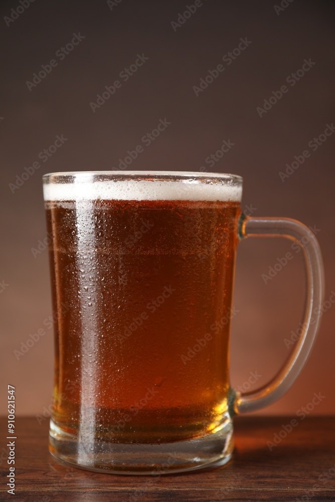 Mug with fresh beer on wooden table against brown background, closeup Mug with fresh beer on wooden table against brown background, closeup