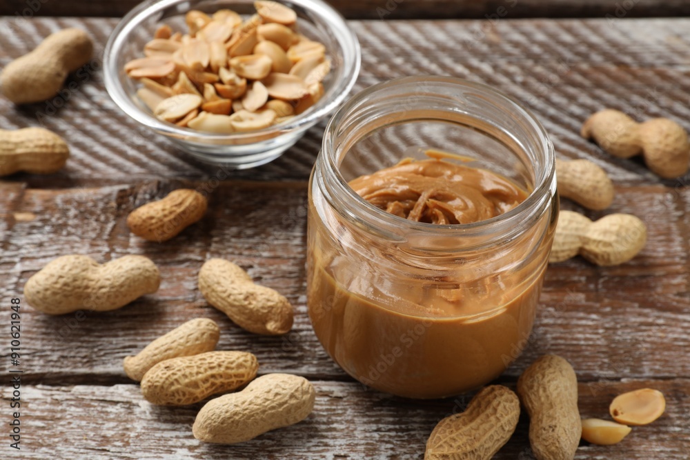 Tasty peanut butter in jar and groundnuts on wooden table Tasty peanut butter in jar and groundnuts on wooden table