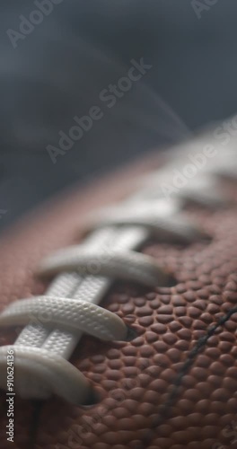 Football ball macro rotating with smoke in studio slow motion, vertical view