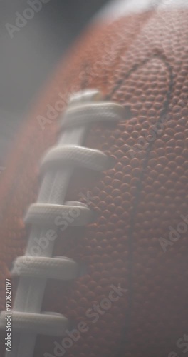 Football ball macro rotating with smoke in studio slow motion, vertical view