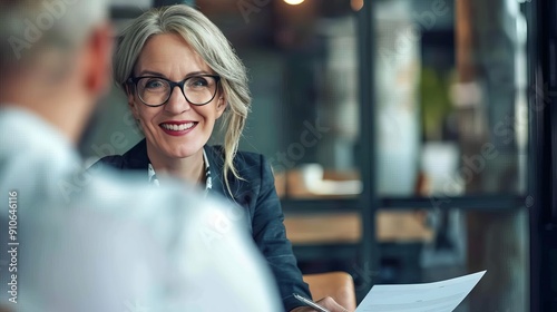 Fototapeta Naklejka Na Ścianę i Meble -  Smiling mature business woman hr holding cv document at job interview. Happy mid aged professional banking manager or lawyer consulting client sitting at workplace in corporate office meeting.