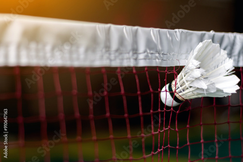 a player hit the shuttlecock so hard that it got stuck in the net, causing it to tear. The powerful shot left a hole in the net, marking a dramatic moment on the court, badminton background concept. photo