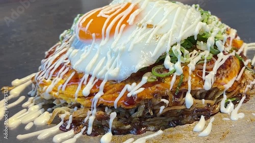 日本のお好み焼き。鉄板の上のお好み焼きにマヨネーズをかけるクローズアップ動画。