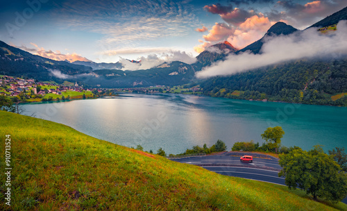 Red van on the parking place in Swiss Alps. Misty summer view of Lungerersee lake. Colorful morning cityscape of Lungern village, Switzerland, Europe. Traveling concept background.. photo