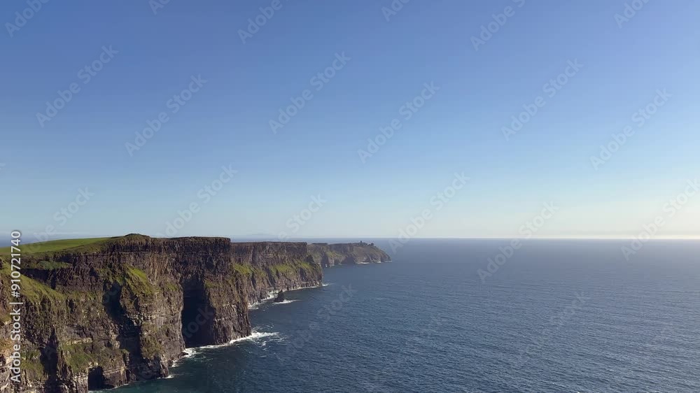 Sunny blue sky day as Cliffs of Moher look over calm blue ocean water Sunny blue sky day as Cliffs of Moher look over calm blue ocean water