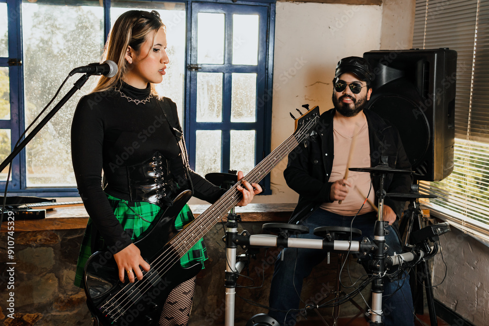 Naklejka premium Woman singer playing bass guitar. Band rehearsing at home. International music day.