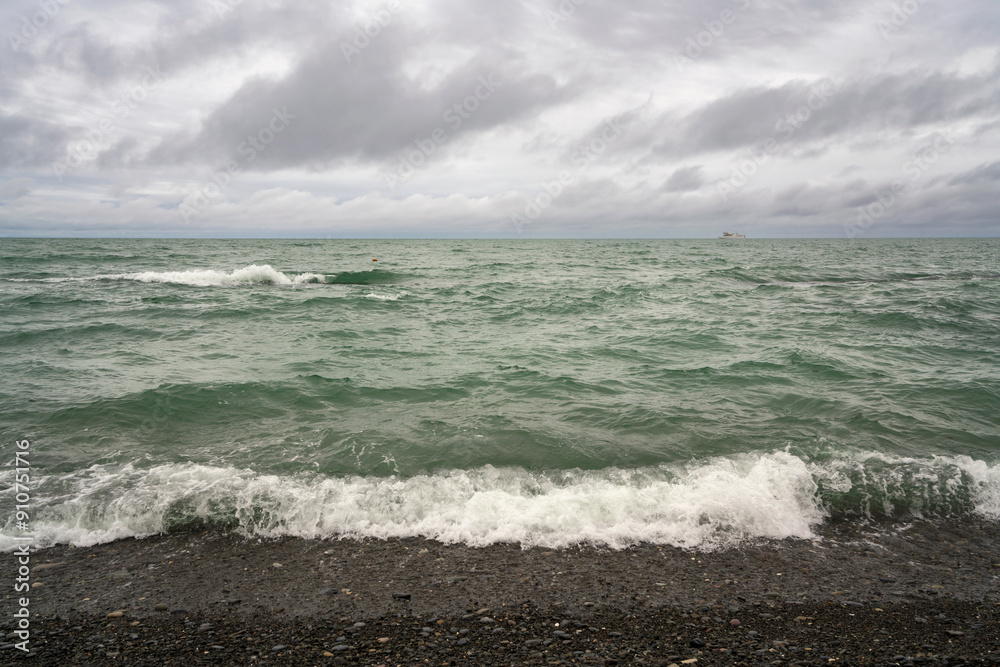 An incoming wave on the Black Sea and a pebble beach on the Sochi coast on a summer day with clouds, Sochi, Krasnodar Territory, Russia An incoming wave on the Black Sea and a pebble beach on the Sochi coast on a summer day with clouds, Sochi, Krasnodar Territory, Russia