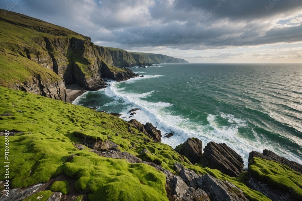 Obraz premium Sea flowing near rough rocky cliffs with uneven surface covered with green moss in coastal area of nature against cloudy sky
