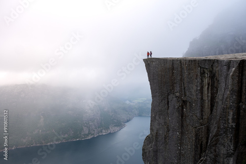 Adventurous Hikers Standing on Preikestolen Cliff Overlooking the Fjord in Norway at Dawn