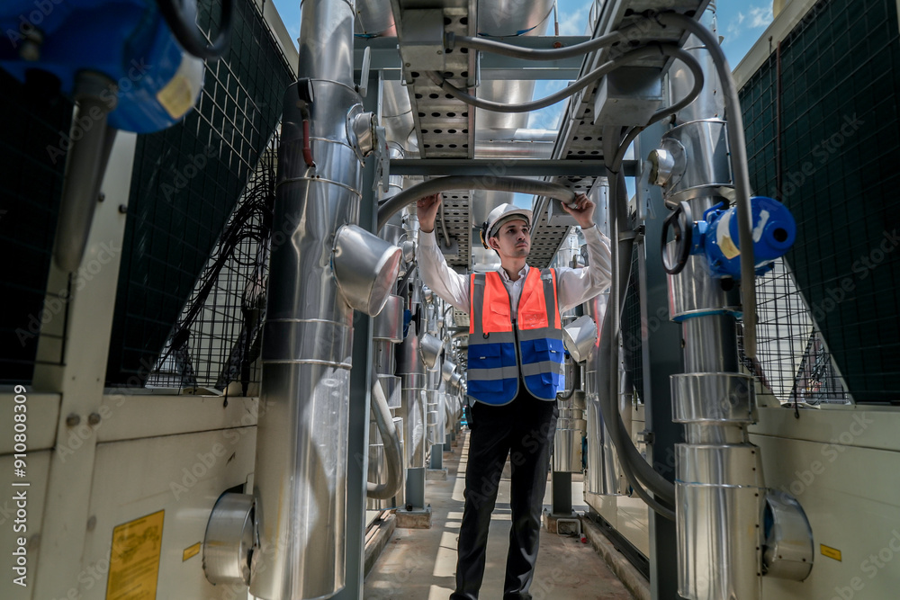 Engineers inspect gas and water pipes for power and cooling in industrial and building systems. workers in safety gear work seriously in oil and gas refining plant with pipes connecting to machinery. Engineers inspect gas and water pipes for power and cooling in industrial and building systems. workers in safety gear work seriously in oil and gas refining plant with pipes connecting to machinery.