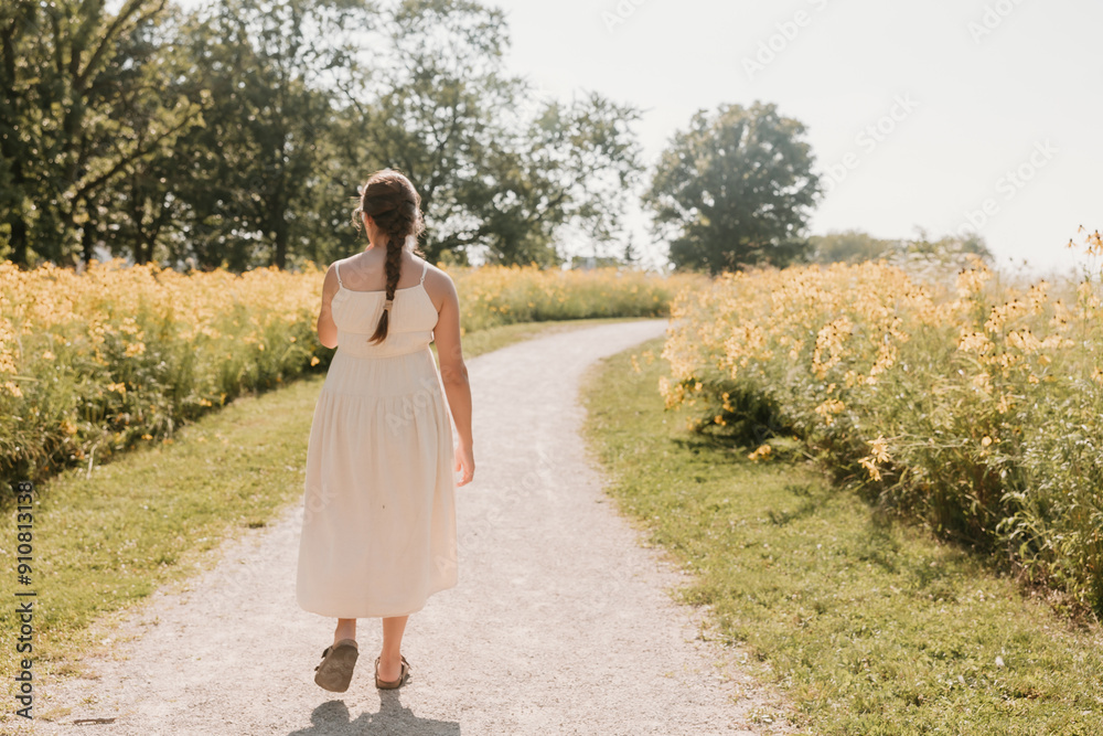 Pregnant woman in linen dress walking on a wildflower path Pregnant woman in linen dress walking on a wildflower path