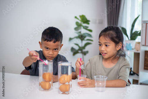 Two children are playing with a science experiment involving water and eggs