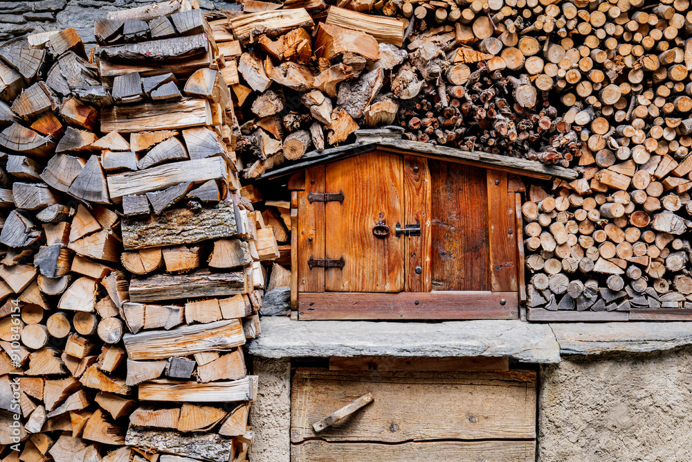Pontechianle, Italy. Wooden logs stacked on the wall of a mountain house. Miniature wooden house for storing tools. Pontechianle, Italy. Wooden logs stacked on the wall of a mountain house. Miniature wooden house for storing tools.