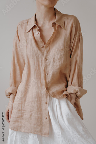 Chic, casual look with a pastel beige, loose-fitting linen button-up shirt and high-waisted white skirt. Soft, neutral tones and relaxed style