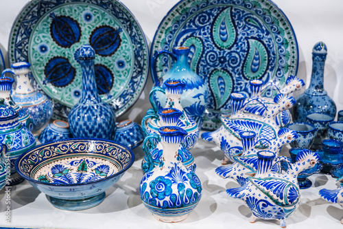 Uzbek ceramic plates, jugs and dishes hand-painted in the oriental shop at the pottery workshop in Uzbekistan photo