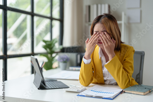 Asian businesswoman is tired, sleepy, has a headache, stressed from work and bored from sitting at a desk for a long time and has office syndrome.