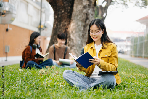 Asian Students are studying the campus park. Young people are spending time together. Reading book, working with laptop and tablet