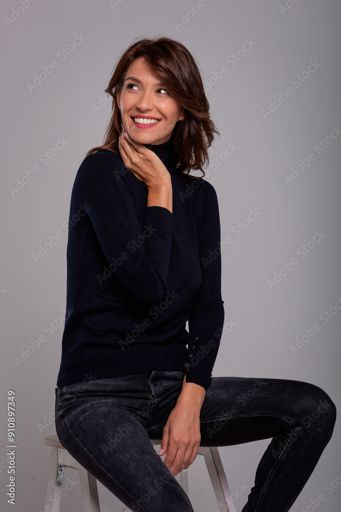 Studio portrait of a mid aged woman sitting against isolated background Studio portrait of a mid aged woman sitting against isolated background