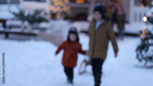 A large friendly family gathered in the yard of their cottage on Christmas to have fun and arrange gifts on a sled. Merry Christmas and New Year concept.