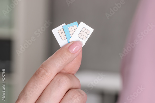 Woman holding SIM cards indoors, closeup view