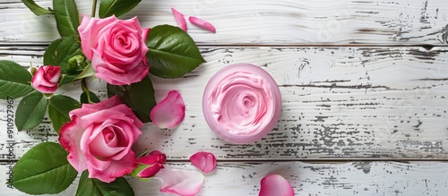 Rose flower and pink moisturizer displayed on a white wood background with ample copy space image photo