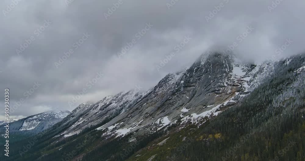 Rugged Rocky Mountainside with some snow. Canadian Mountain Landscape with Trees and Dramatic Cloudy Sky. British Columbia, Canada. Rugged Rocky Mountainside with some snow. Canadian Mountain Landscape with Trees and Dramatic Cloudy Sky. British Columbia, Canada.