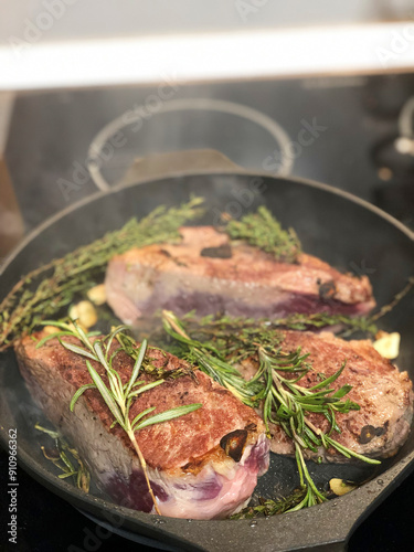 steak with rosemary and garlic on a frying pan in the kitchen photo